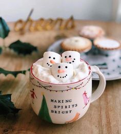 a cup filled with marshmallows sitting on top of a table next to cookies