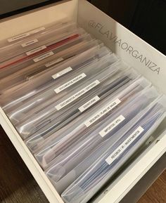 an open drawer with several clear plastic containers in it and labels on the bottom shelf