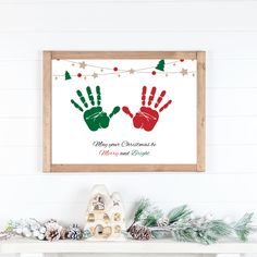 a christmas card with two hand prints hanging on the wall next to a fireplace mantel