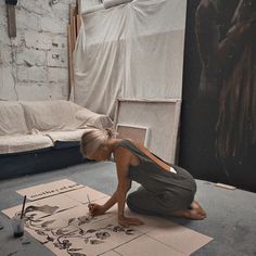 a woman is sitting on the floor working on some art work in front of her