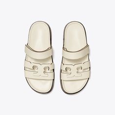 Minimal and effortless, our Ines Sport slide is updated with sharp lines featuring a split take on our signature Double T. A velcro strap secures the foot and an ergonomic footbed — cupped by a rubber sole — adds supreme comfort. Ivory Sandals, Tory Burch Sandals, Loafer Shoes Women, Sandals White, White Sandals, Footwear Design Women, Designer Sandals, Handbag Shoes, Tory Burch Shoes