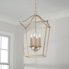 a chandelier hanging from the ceiling in a room with windows and white walls