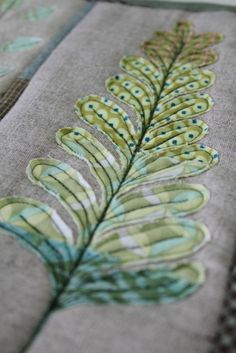 a close up of a piece of cloth with a pattern on it and a green leaf