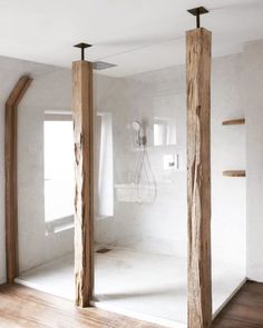 an empty room with two wooden poles in the middle and a shower head mounted to the wall