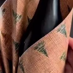 a person holding a bottle of wine in their left hand and wearing a tie with pineapples on it