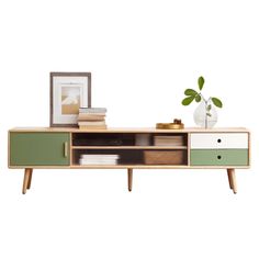 a green and white cabinet with drawers on it's sides, next to a potted plant