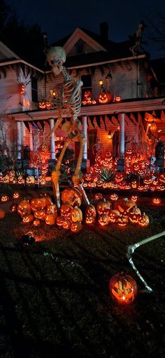 halloween decorations in front of a house with skeletons and pumpkins on the lawn at night