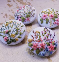 four embroidered buttons with flowers on them