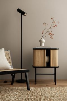 a living room with a chair, table and lamp on the sideboard next to it