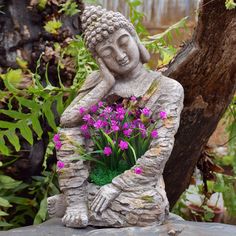 a buddha statue sitting on top of a rock holding a bouquet of flowers in it's lap