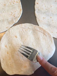 a hand holding a fork over some tortillas