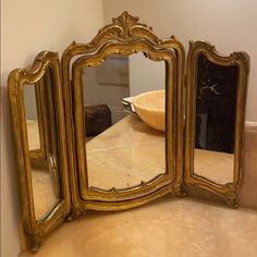 an ornately decorated gold mirror sits on a counter