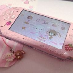 a pink cell phone sitting on top of a table next to a small stuffed animal