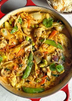 a pan filled with food sitting on top of a table next to a bowl of rice