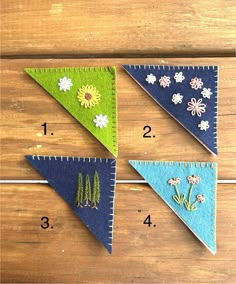 four different colored felt pennants with flowers on them and numbers in the bottom left corner