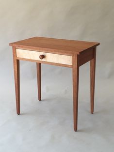 a small wooden table with two drawers on one side and a drawer on the other