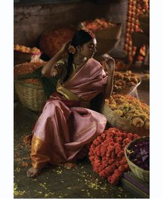 a woman sitting on the ground in front of baskets filled with flowers and other items