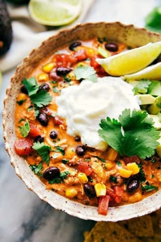 a bowl of mexican soup with sour cream and tortilla chips on the side