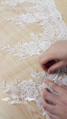 the woman is working on her white lace trimming project with scissors and threading