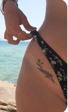 a woman's stomach with a flower tattoo on her belly and the ocean in the background