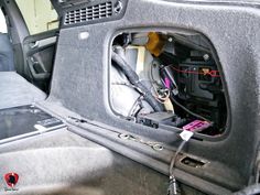 the inside of a car with its door open and wires in it's trunk