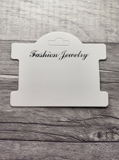 a white card with the word fashion jewelry on it sitting on top of a wooden table