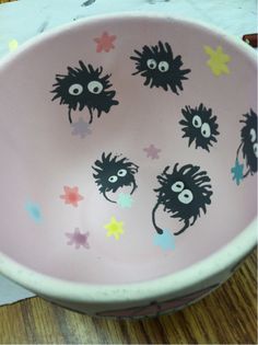 a pink bowl with black cats painted on the side and stars in the bottom, sitting on a wooden table