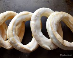 four pretzels sitting on top of a black surface next to each other with white frosting