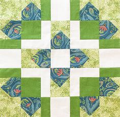 a green and white quilt with blue and red designs on the center, along with two different colored blocks