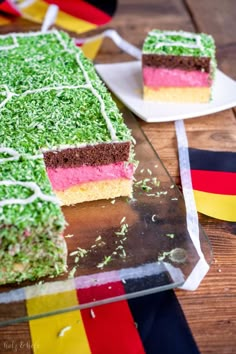 two pieces of cake sitting on top of a wooden table next to flags and ribbons