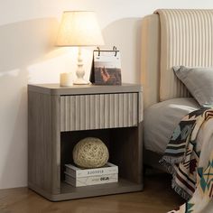 a nightstand with a book on it next to a bed