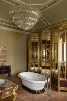 a fancy bathroom with an ornate chandelier above the bathtub and mirror cabinet