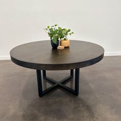 a wooden table with two potted plants on it's top, against a white wall