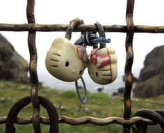 two hello kitty headphones hanging from a wooden fence with green grass in the background