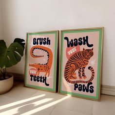 two framed posters on the wall with words brush your teeth and wash your paws in front of a potted plant