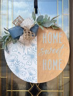 a wooden sign that says home sweet home hanging on a door with blue and white flowers