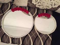 two mirrors with red roses on them are sitting on a bed next to a pillow