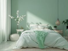 a bedroom with green walls, white furniture and flowers in vases on the bed