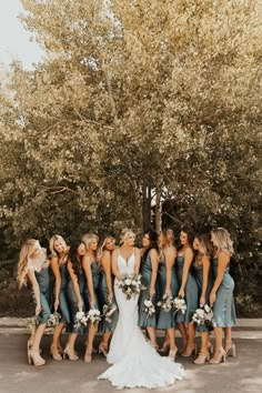 a group of bridesmaids standing in front of a tree