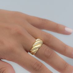 a woman's hand wearing a gold ring with white stones on the middle finger