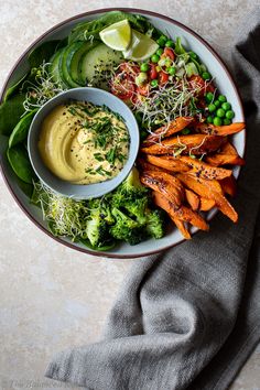 two hands holding a bowl of vegetables and dip