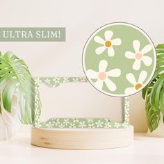 there is a green and white photo frame with flowers on it next to a potted plant