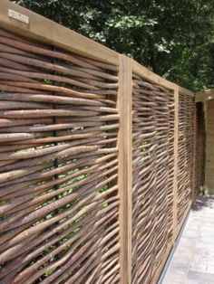 a wooden fence is shown in front of a brick wall and tree lined sidewalk area