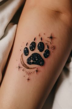 a dog paw tattoo with stars and crescent moon on the left side of the leg