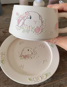 two white plates with designs on them are being held by someone's hand