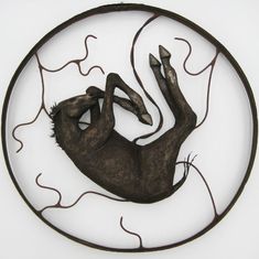 a metal sculpture of a person laying on their back in the middle of a circle