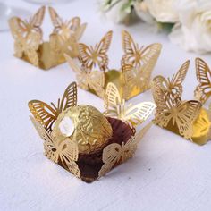 some gold butterflies sitting on top of a white table cloth with flowers in the background