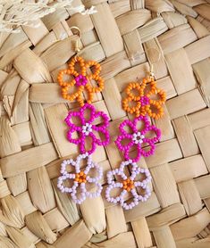 two pairs of colorful beaded earrings sitting on top of a woven basket