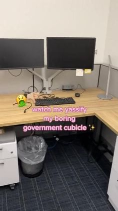 an office cubicle with two computer monitors and a keyboard on the desk that says watch me yaasfy my boring government cubicle