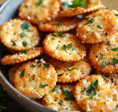 a bowl filled with crackers covered in parmesan cheese and garnished with herbs